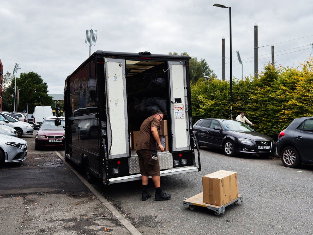 Delivery driver loading packages from van in Manchester
